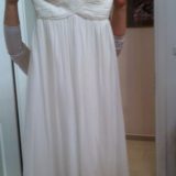 אדם מחזיק שמלת סטרפלס לבנה מול דלת ארון. לשמלה מחוך צמוד וחצאית נשפכת. פני האנשים אינם נראים. הרקע כולל דלת לבנה סגורה וחלק מחדר שינה.