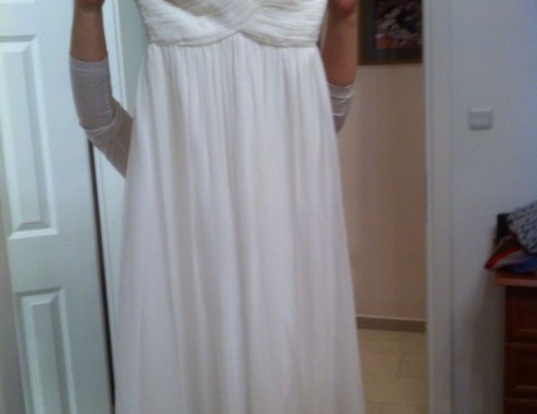 אדם מחזיק שמלת סטרפלס לבנה מול דלת ארון. לשמלה מחוך צמוד וחצאית נשפכת. פני האנשים אינם נראים. הרקע כולל דלת לבנה סגורה וחלק מחדר שינה.