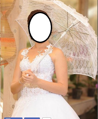 כלה בשמלת כלה תחרה לבנה מחזיקה שמשיית תחרה. היא עומדת בפנים עם קיר עץ ברקע.