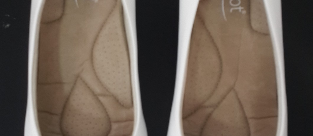 זוג נעלי נשים לבנות במבט מלמעלה, מציגות את המדרסים המרופדים בצבע בז עם עיצוב מרקם לתוספת נוחות.